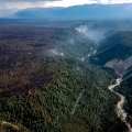 Aerial view of the Chetaslina Fire (#606) showing burned area, green vegetation, minimal smoke, and rain in the distance.