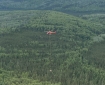 Red helicopter with with long line and cargo net hauling unneeded fire supplies and trash back to helibase